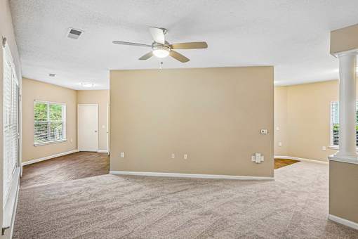 A spacious room with a ceiling fan and carpeted floor.