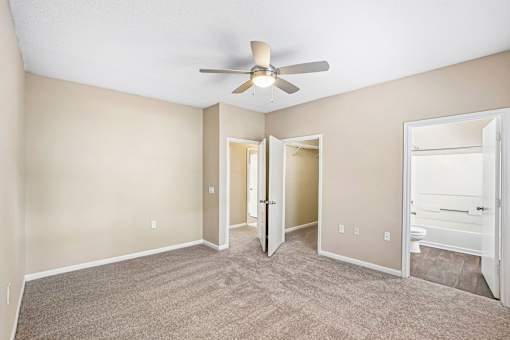 A room with a ceiling fan and carpeted floor.