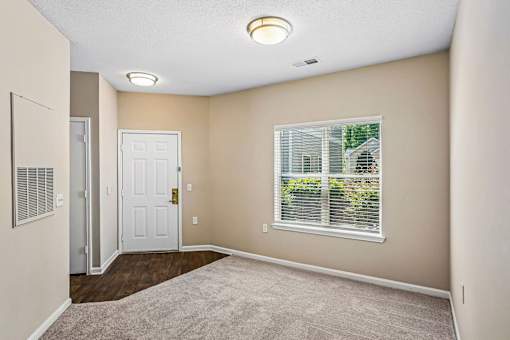 A room with a white door and a window with blinds.