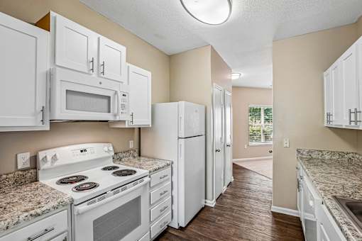 A kitchen with white appliances and cabinets.