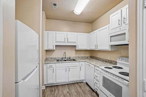 A kitchen with white appliances and cabinets.