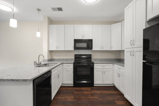 an empty kitchen with white cabinets and black appliances