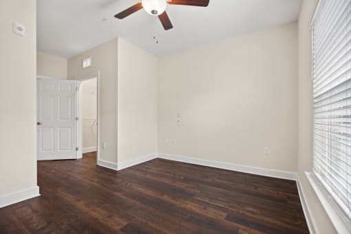 an empty living room with wood floors and a ceiling fan