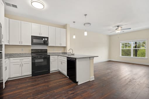 an empty kitchen with white cabinets and a black stove and refrigerator