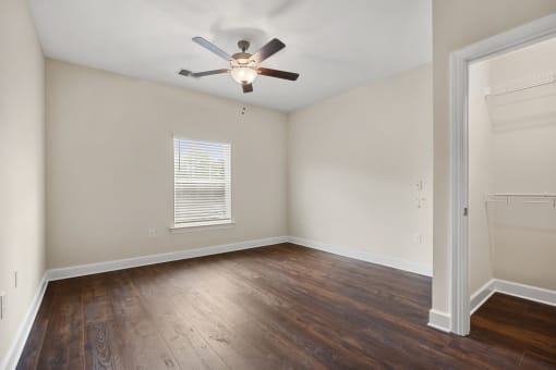 an empty living room with wood floors and a ceiling fan