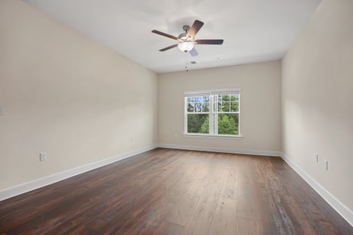 an empty living room with wood floors and a ceiling fan