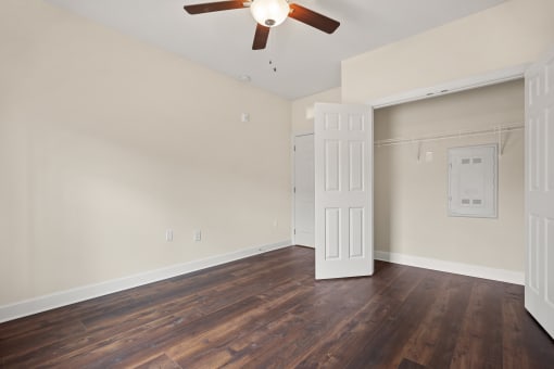 an empty living room with wood floors and a ceiling fan