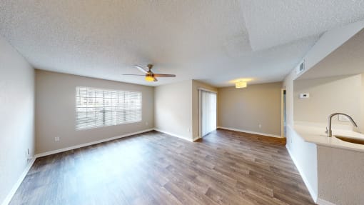 an empty living room with a ceiling fan