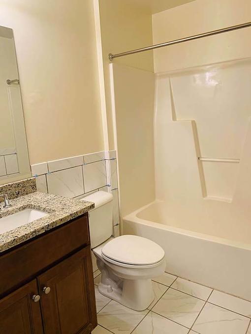 A white toilet sits in a bathroom next to a sink and a bathtub.