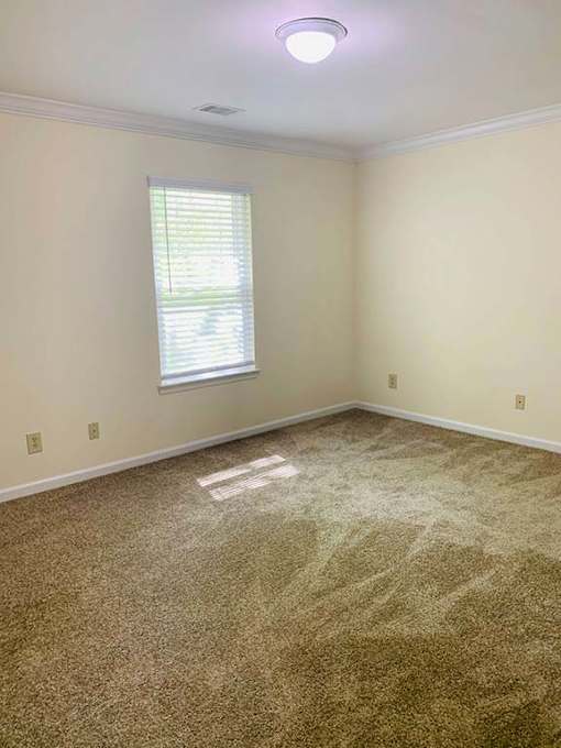 A room with a window and a carpeted floor.