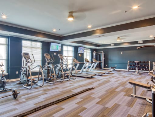 a fitness room with treadmills and weights on a wooden floor