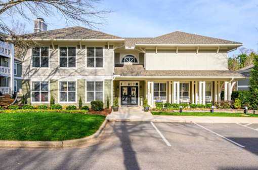 A large, two-story building with a front porch and a driveway in front.