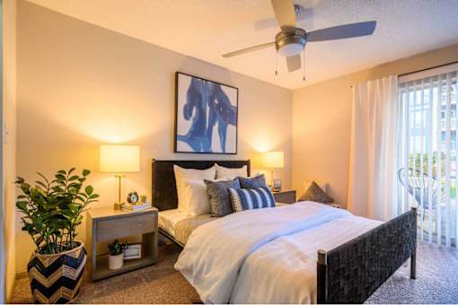 A bedroom with a large bed and a ceiling fan.