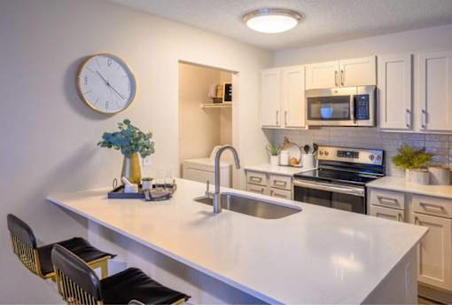 A kitchen with a white countertop and a clock on the wall.