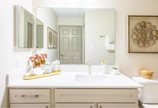 A bathroom with a white sink and a large mirror.