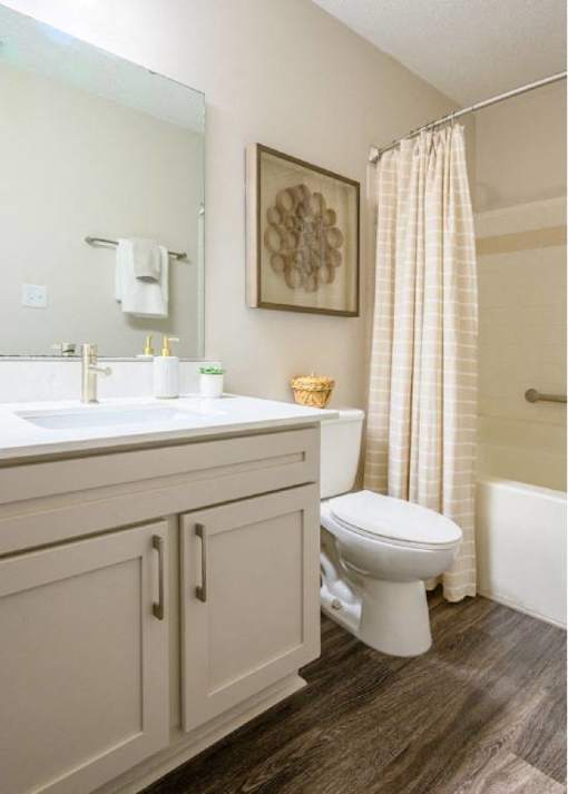 A white toilet sits in a bathroom with a white sink and a shower curtain.