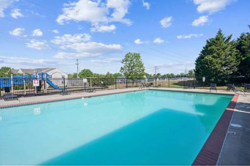 A large outdoor swimming pool with a slide in the background.