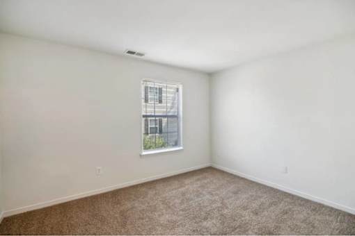 A room with a window and carpeted floor.