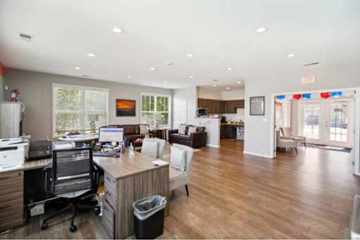A spacious office with a wood desk and a black trash can.