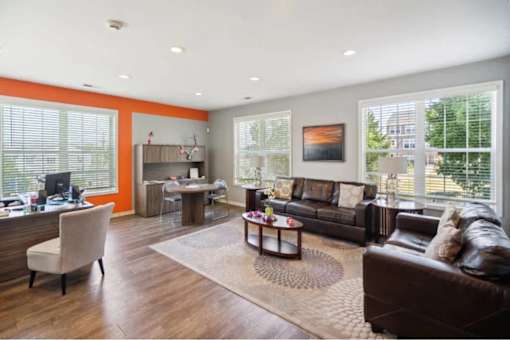 A living room with a brown leather couch and a wooden floor.