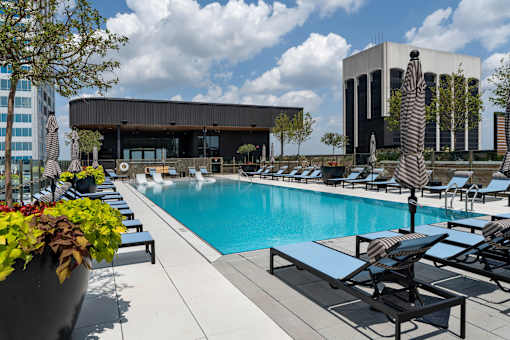 A pool area with lounge chairs and a building in the background.