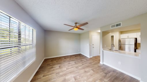 a living room with a large window and a ceiling fan