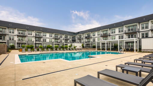 a swimming pool with lounge chairs in front of an apartment building at Ainsworth, Virginia, 23228