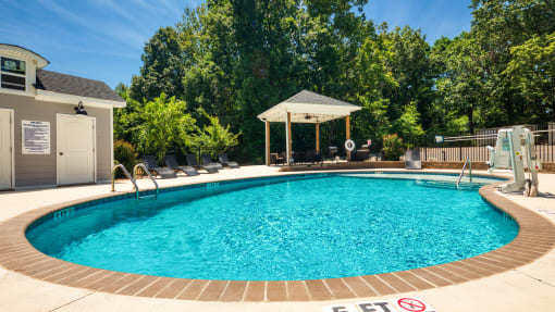 a swimming pool in a backyard with a pool house and a resort style pool