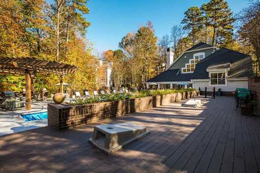 A wooden deck with a hot tub and a house in the background.