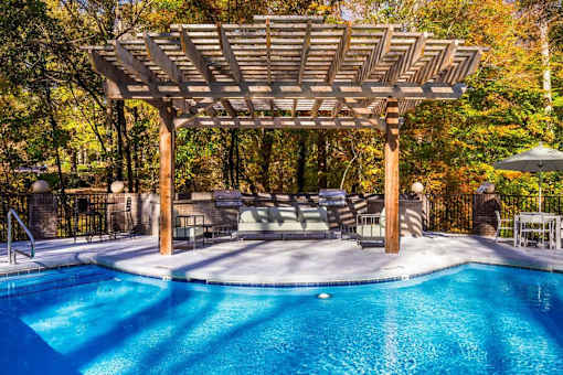 A pool with a wooden pergola over it.