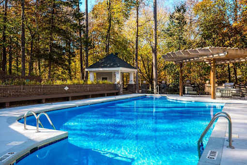 A swimming pool surrounded by trees and a gazebo.