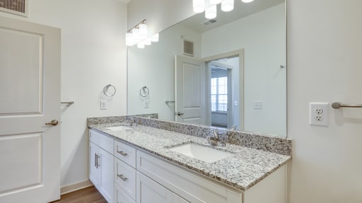 a bathroom with white cabinets and granite counter tops and a large mirrorat The Walker Virginia Center in Glen Allen, VA