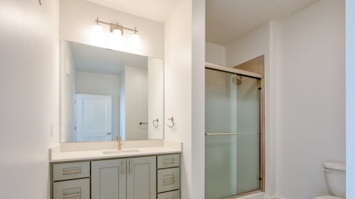 a bathroom with a sink and a mirror and a shower at The Port at East Beach Apartments and Marina, Virginia