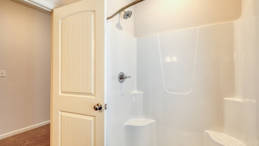 a white shower in a bathroom with a door