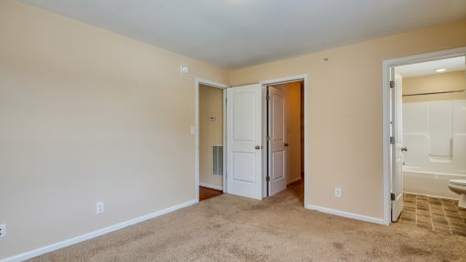 a bedroom with a door to a bathroom and a closet