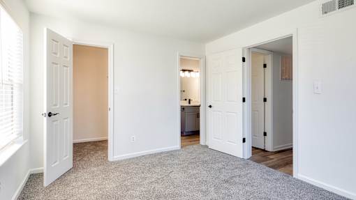 A white room with a carpeted floor and a doorway leading to another room.