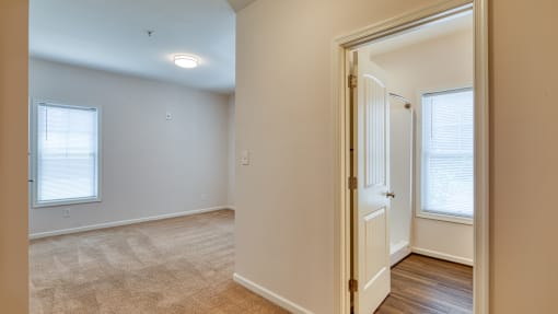 a living room with a door and a hallway to a bedroom