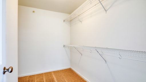 an empty closet with white walls and a hanging rack on the wall