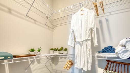 a white robe hanging on a rack in a closet
