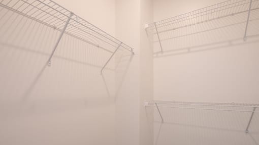 a walk in closet with white walls and shelves and a white closet door with wire at The Port at East Beach Apartments and Marina, Norkfolk