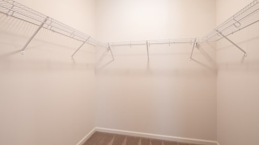 a room with white walls and wire racks on the ceiling