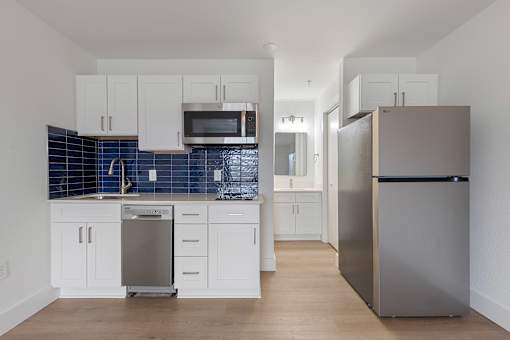 A kitchen with white cabinets and a blue tile backsplash.