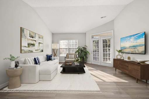 A living room with a white sofa, a coffee table, and a painting on the wall.