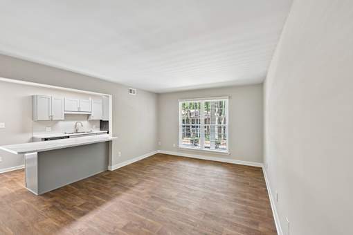 A kitchen with a window and wooden floors.