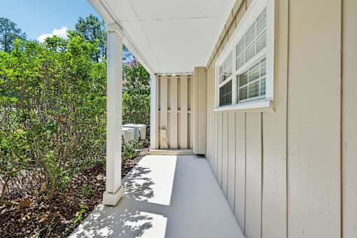 A white porch with a white railing and a white window.