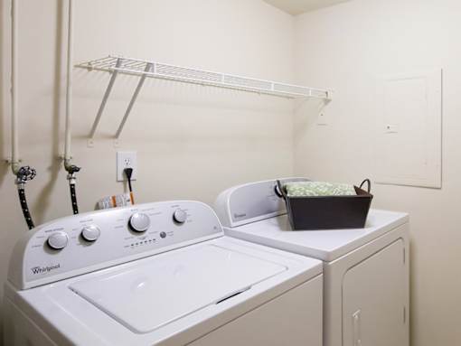 A white Whirlpool washing machine and dryer in a small laundry room.