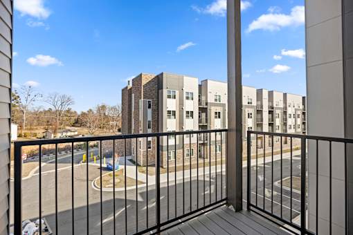 A view from a balcony overlooking a parking lot and apartment buildings.
