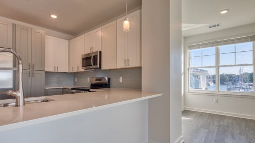 a kitchen with white cabinets and a large window at The Port at East Beach Apartments and Marina, Virginia, 23518