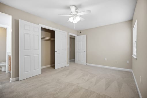 an empty living room with white doors and a ceiling fan