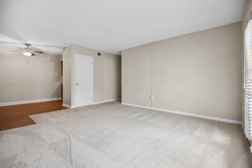 an empty living room with a closet and a ceiling fan